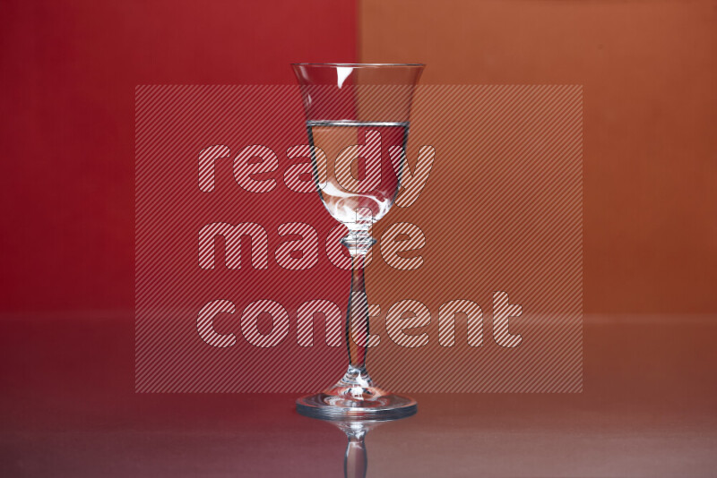 The image features a clear glassware filled with water, set against red and dark orange background