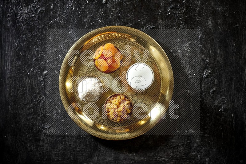 Dried fruits in metal bowls with sobya on a tray in dark setup