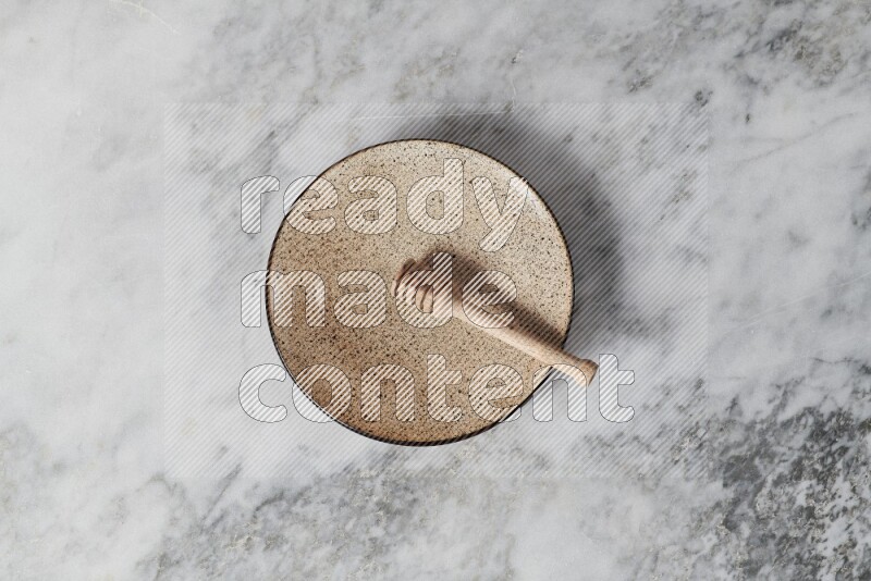 Multicolored pottery plate with wooden honey dipper in it on grey marble background