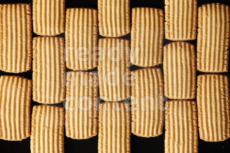 Golden biscuits filling the frame on black background