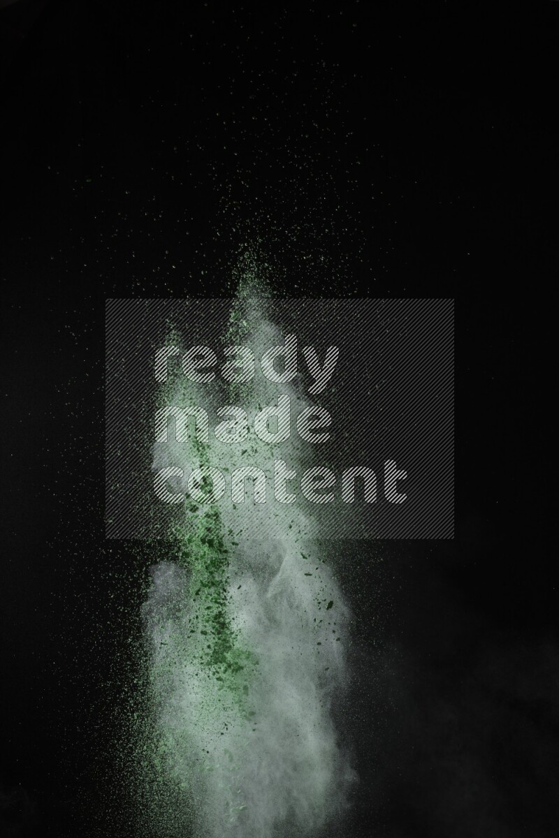 A side view of green powder explosion on black background