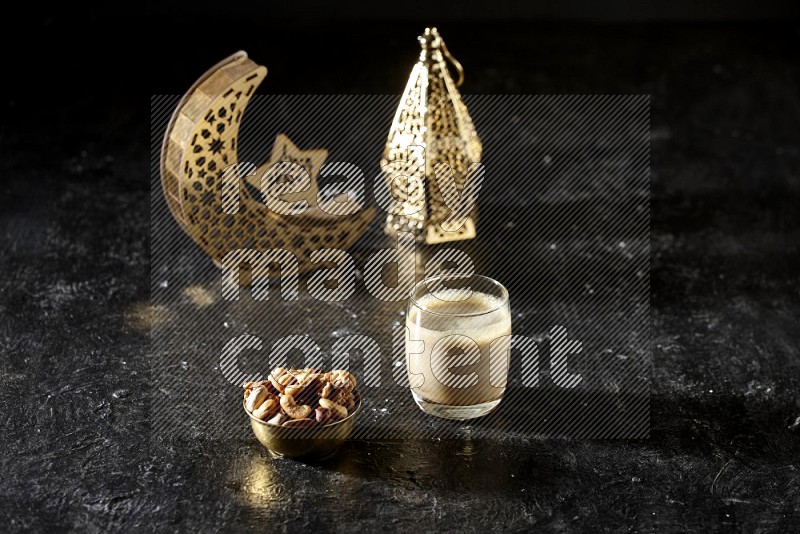 Nuts in a metal bowl with Nuts smoothie beside golden lanterns in a dark setup