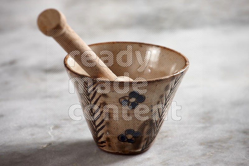 Decorative Pottery Bowl with wooden honey handle in it, on grey marble flooring, 15 degree angle