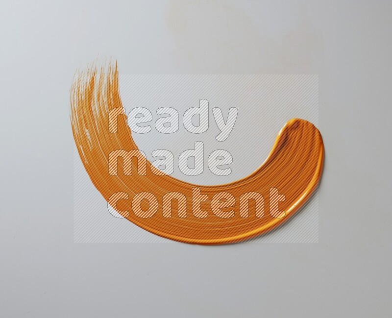 An orange half circular painting brush stroke on white background