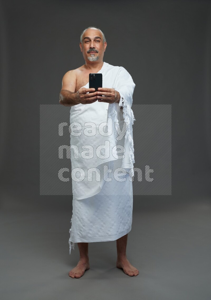 A man wearing Ehram Standing taking selfie on gray background