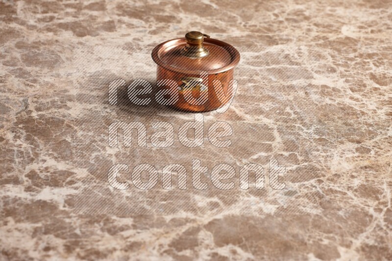 A small copper pot on beige marble background