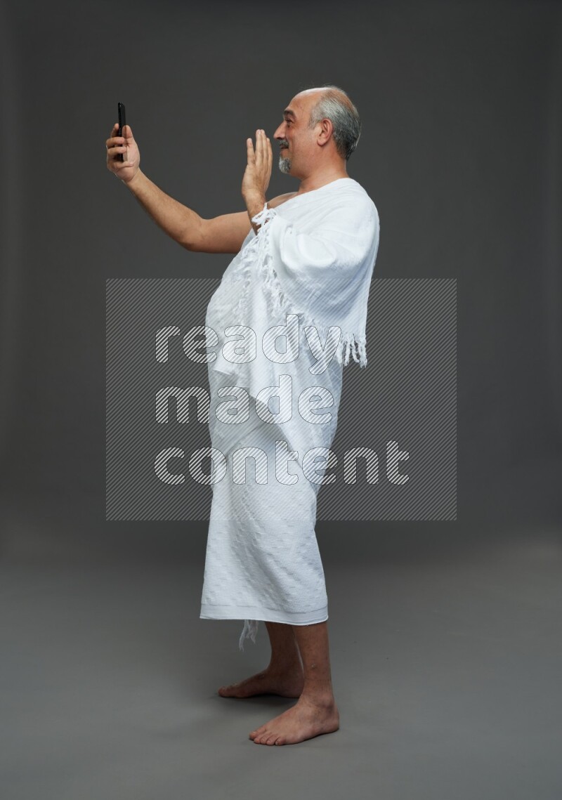 A man wearing Ehram Standing taking selfie on gray background