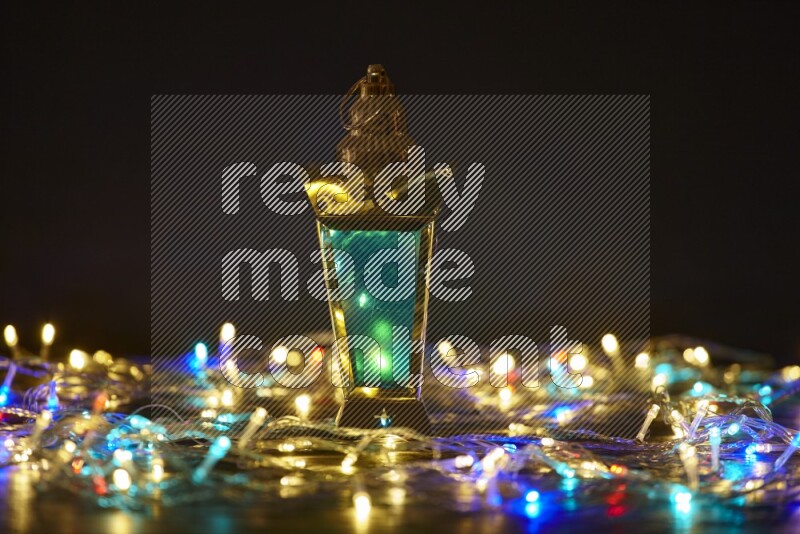 A traditional ramadan lantern surrounded by glowing fairy lights in a dark setup