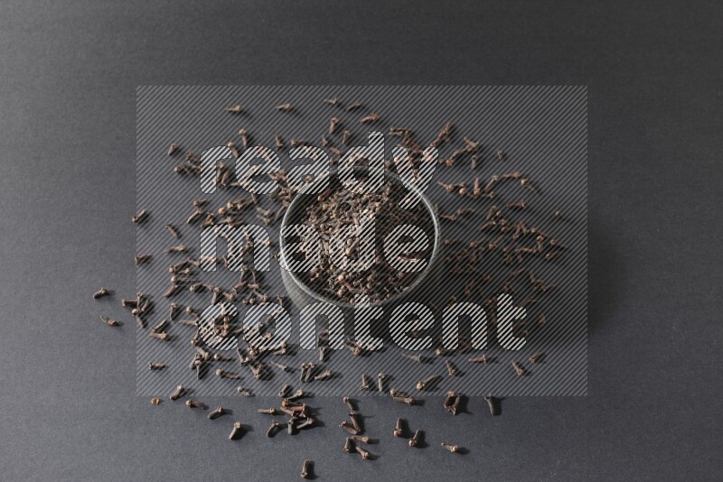 وعاء فخاري أسود ممتلئ بحبوب القرنفل علي خلفية سوداء