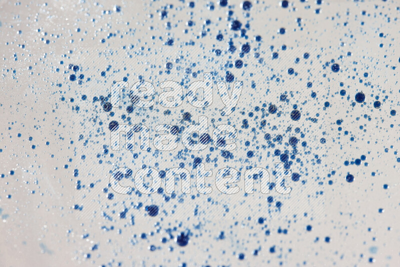 لقطات مقربة لقطرات ألوان مائية زرقاء على سطح الزيت على خلفية بيضاء