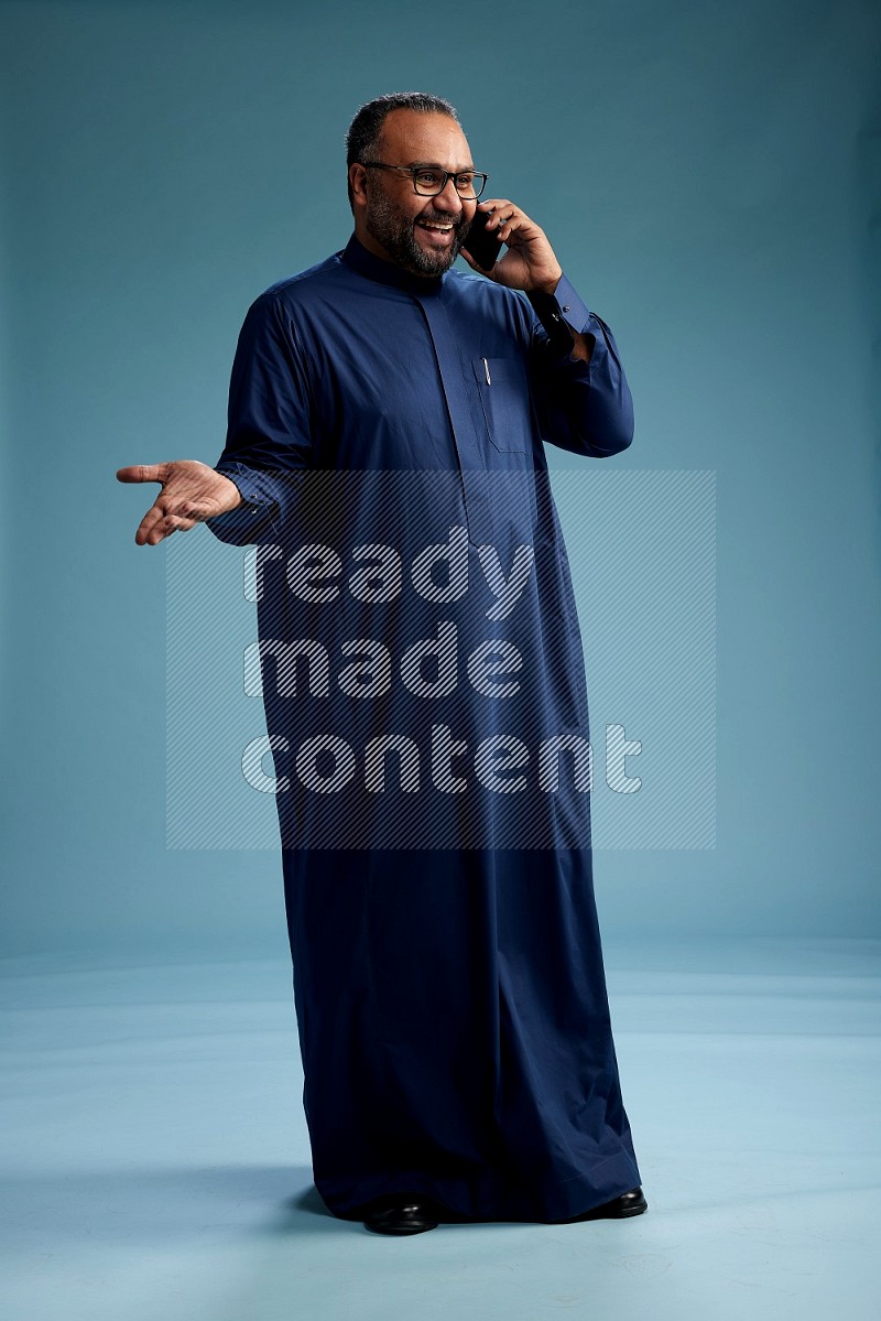 Saudi Man without shimag Standing talking on phone on blue background