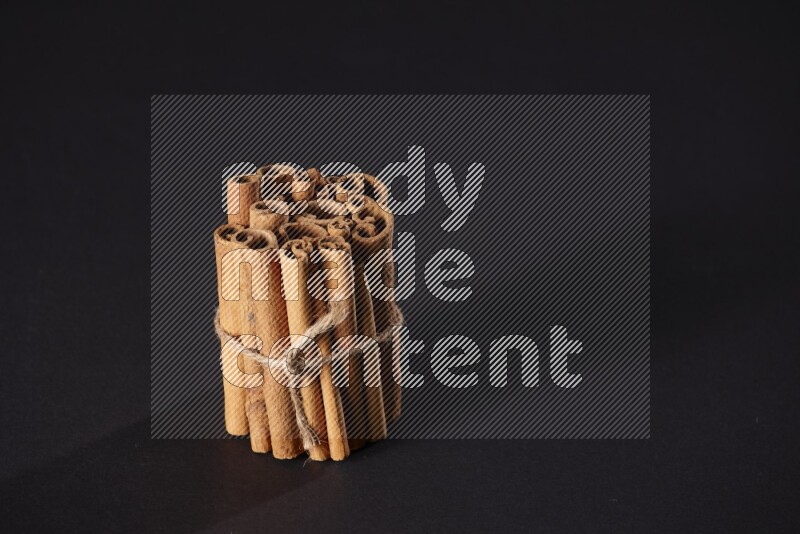 A bounded stack of cinnamon sticks on black background