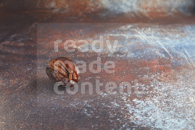 one pecan stuffed madjoul date on a rustic reddish background