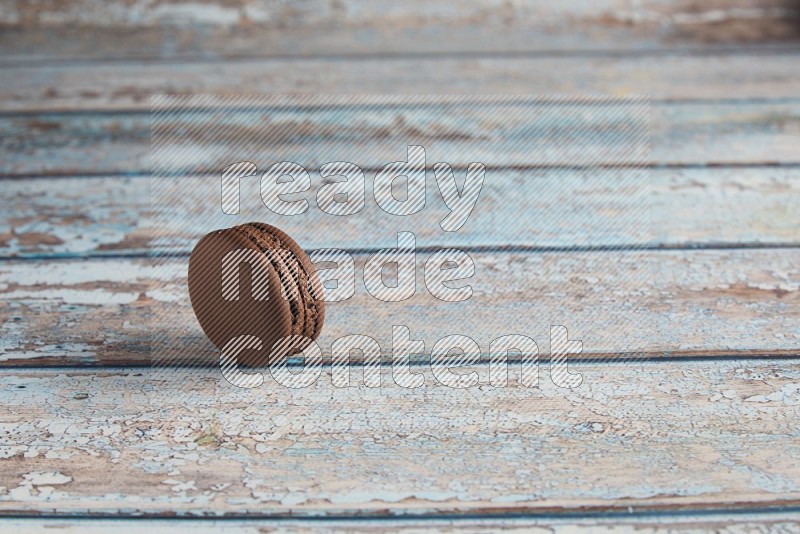 45º Shot of Brown Dark Chocolate macaron on light blue wooden background