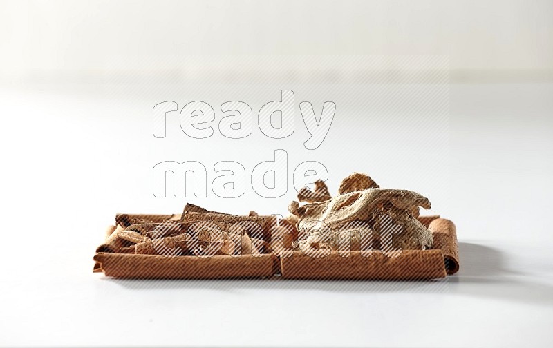 2 squares of cinnamon sticks full of cinnamon and dried ginger on white flooring