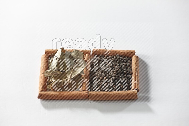 2 squares of cinnamon sticks full of black peppers and bay laurel leaves on white flooring