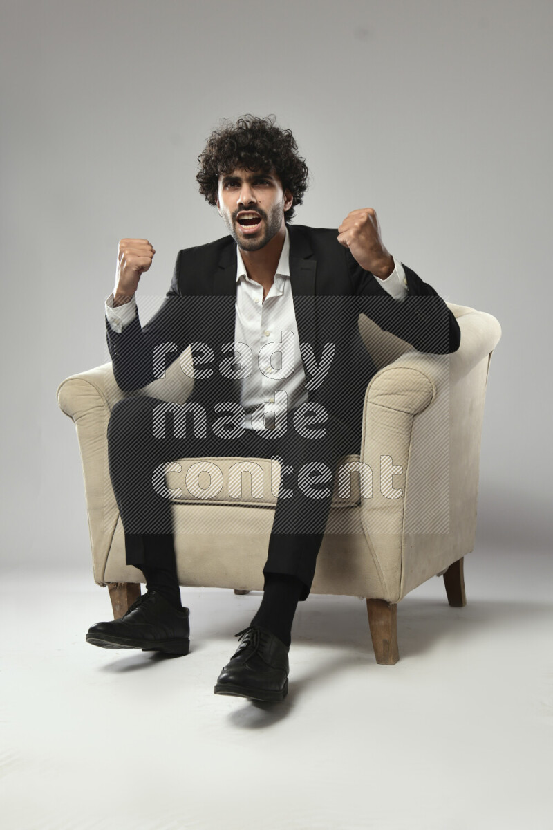 A man wearing formal sitting on a chair making a hand gesture on white background