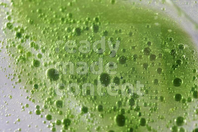 Close-ups of abstract green watercolor drops on oil Surface on white background