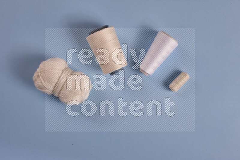 مجموعة من أدوات الخياطة والتفصيل بيضاء اللون على خلفية زرقاء