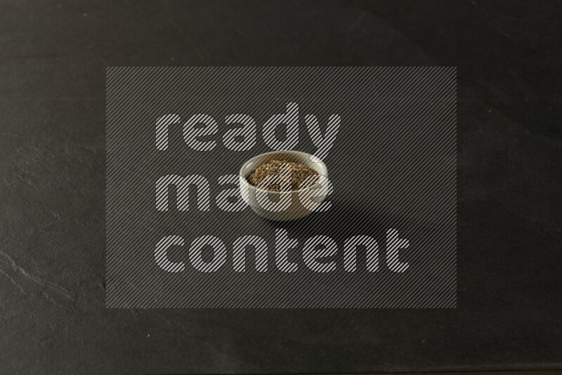 white ceramic round sauce bowl filled with herbs on grey textured countertop