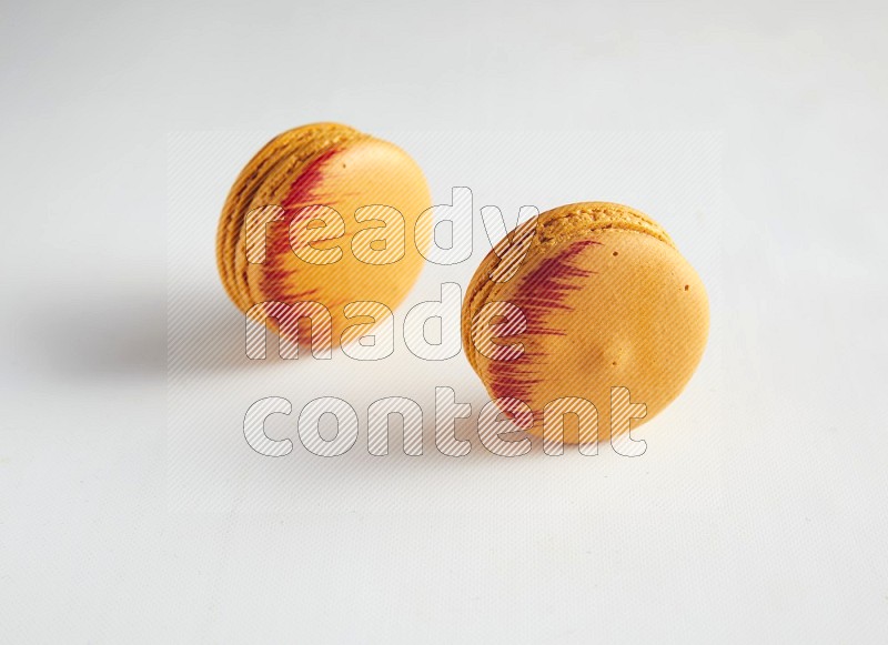 45º Shot of two orange Exotic macarons on white background