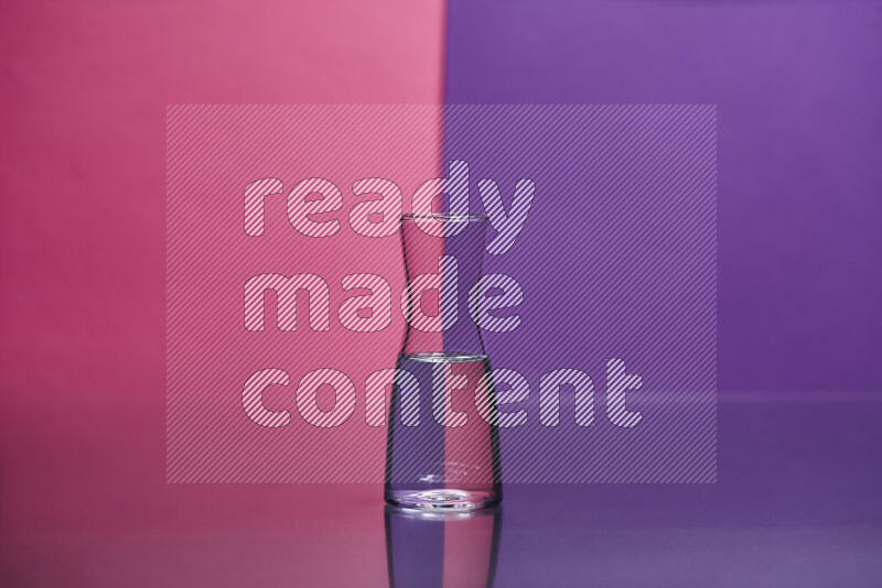 The image features a clear glassware filled with water set against pink and purple background