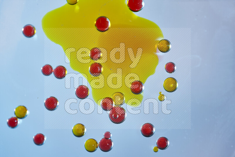 Close-ups of abstract yellow and red watercolor drops on oil Surface on blue background