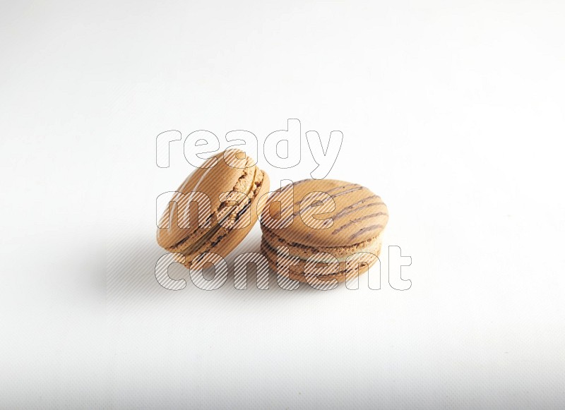45º Shot of of two assorted Brown Irish Cream, and light brown  Almond Cream macarons on white background