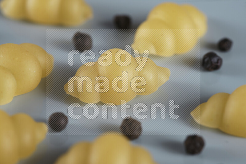 Raw pasta with different ingredients such as cherry tomatoes, garlic, onions, red chilis, black pepper, white pepper, bay laurel leaves, rosemary, cardamom and mushrooms on light blue background