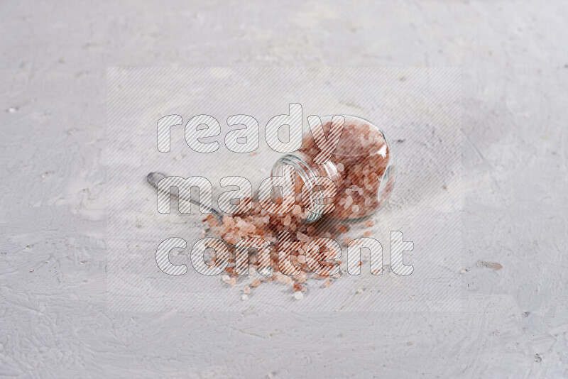 A glass jar full of coarse himalayan salt crystals on white background