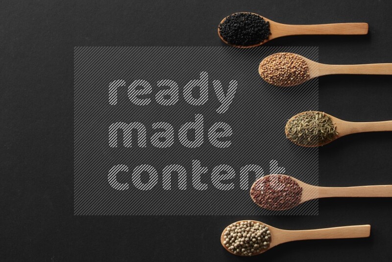 الفلفل الأسود وحبوب الخردل وحبة البركة وحب الرشاد والكمون و حبوب الكتان في معالق خشبية علي خلفية سوداء