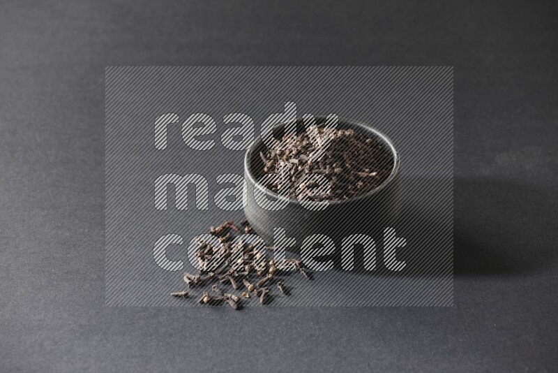 وعاء فخاري أسود ممتلئ بحبوب القرنفل علي خلفية سوداء