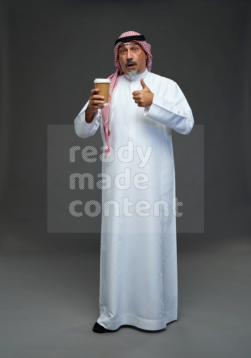 Saudi man with shomag Standing holding paper cup on gray background