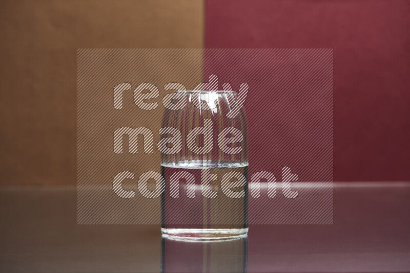 The image features a clear glassware filled with water, set against brown and dark red background