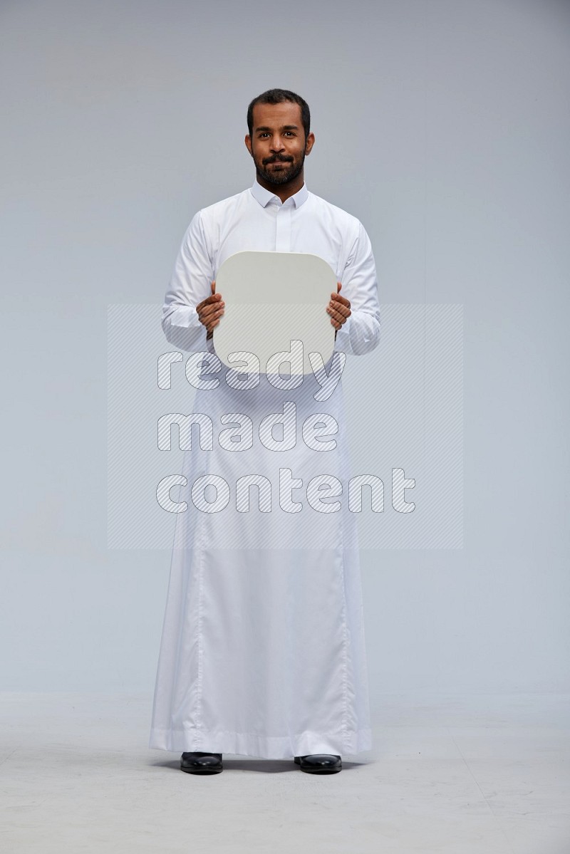 Saudi man wearing Thob standing holding social media sign on Gray background