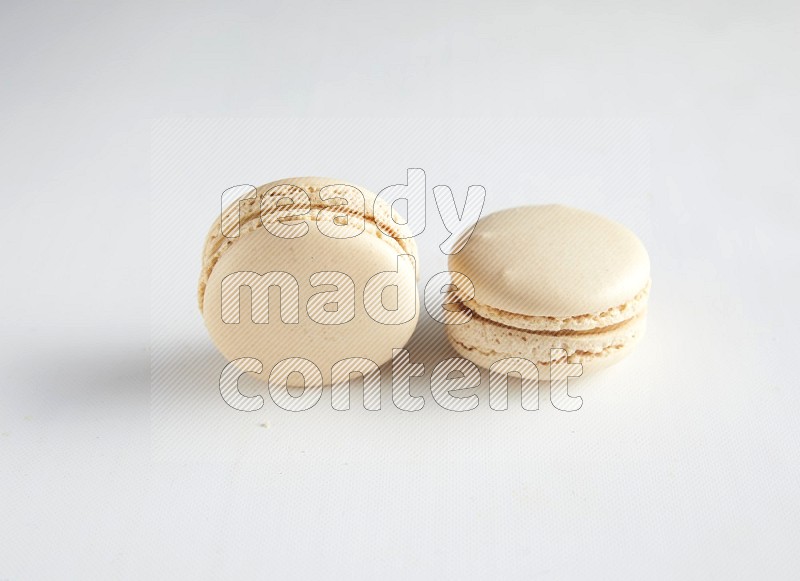 45º Shot of two White Caramel fleur de sel macarons on white background