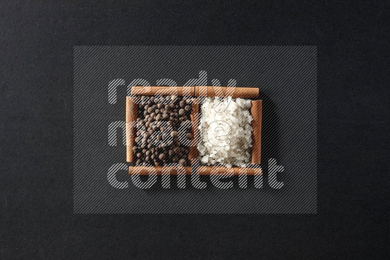 2 squares of cinnamon sticks full of white salt and allspice on black flooring