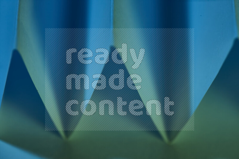 صورة مجردة مقربة تظهر طيات ورقية هندسية حادة بتدرجات اللون الأخضر والأزرق