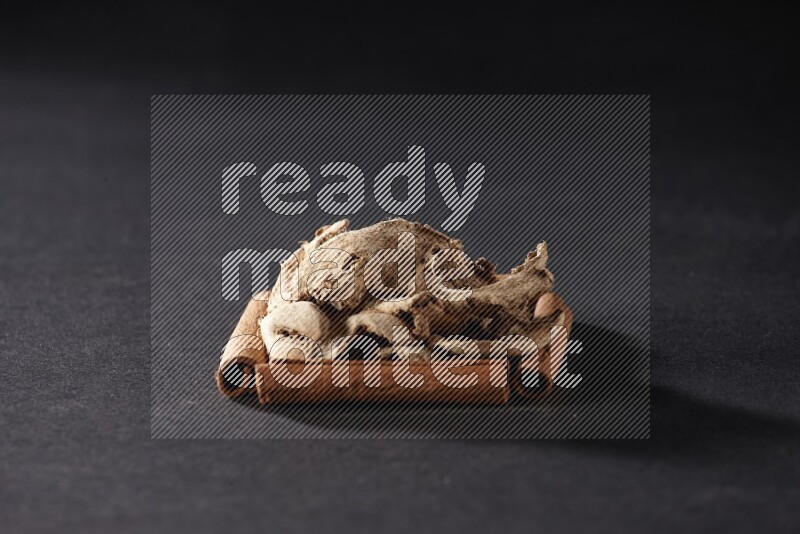 A single square of cinnamon sticks full of dried ginger on black flooring