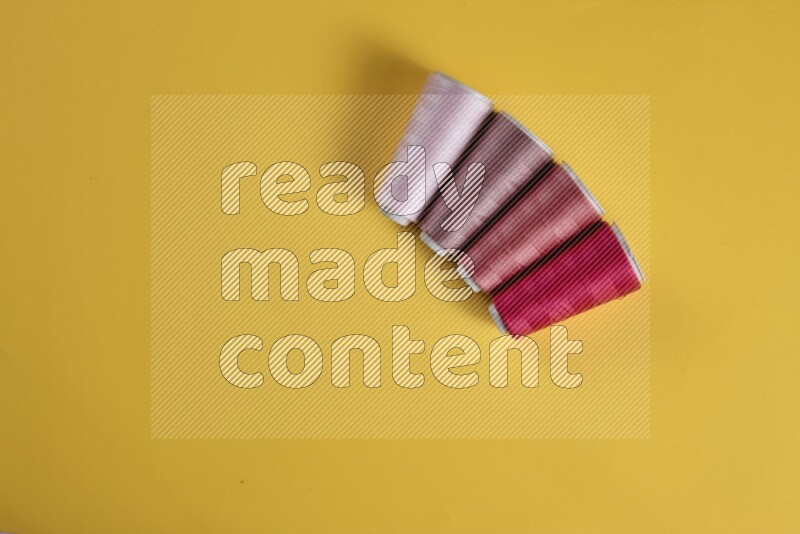 A pink collection of sewing and tailoring tools arranged on a yellow background