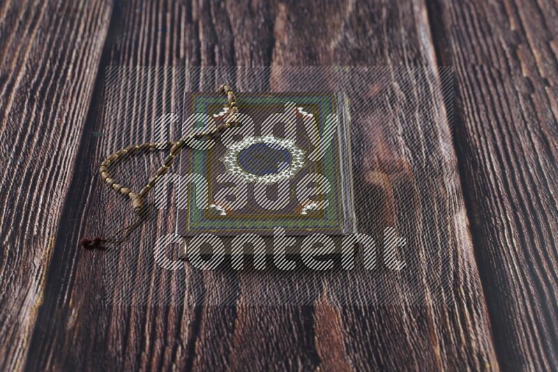 Quran with a prayer beads on wooden background