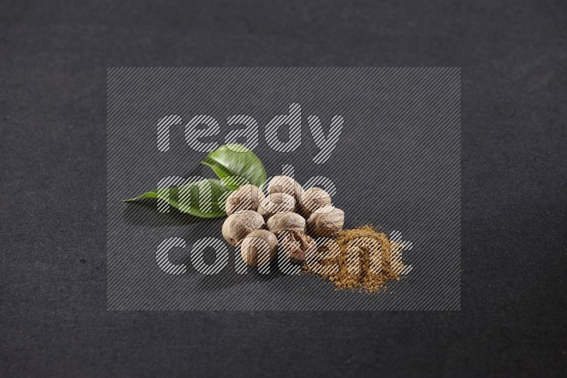 Nutmeg seeds with nutmeg powder beside it on a black flooring in different angles