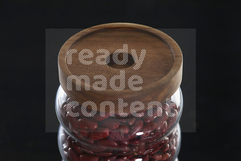 Red kidney beans in a glass jar on black background