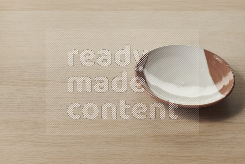 A multicolored pottery plate on light wooden background