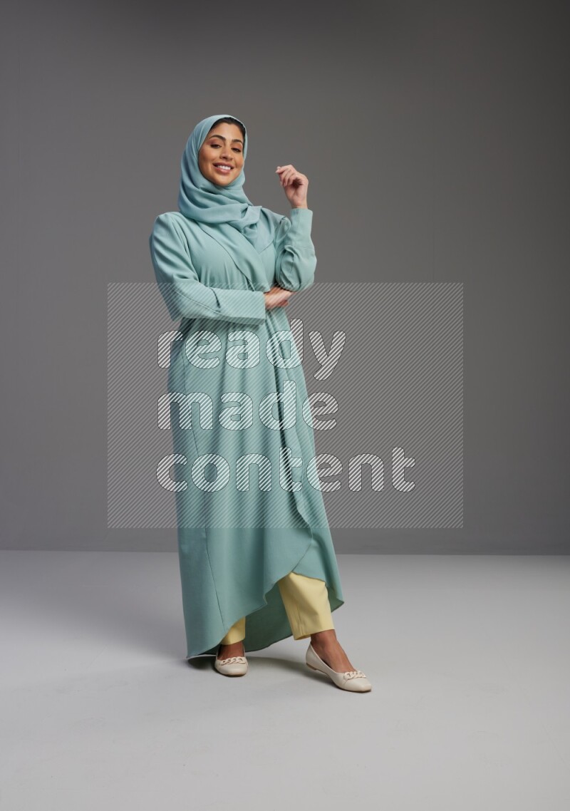 Saudi Woman wearing Abaya standing interacting with the camera on Gray background