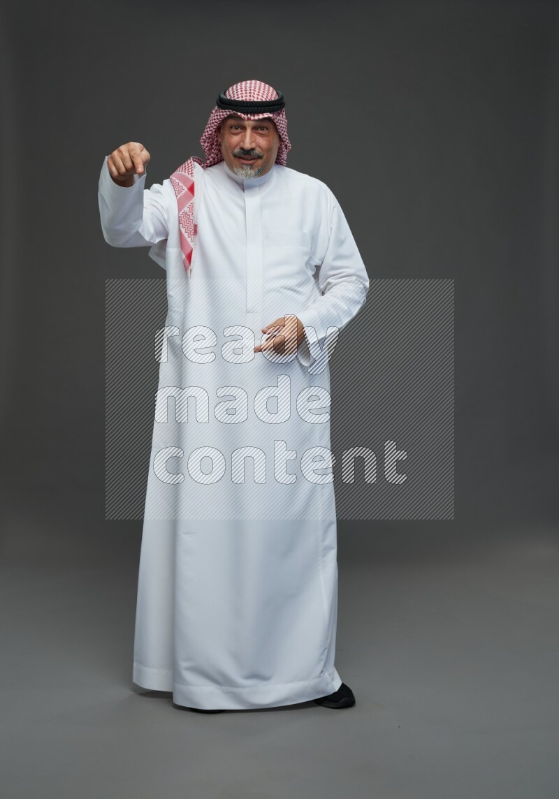 Saudi man with shomag Standing Interacting with the camera on gray background