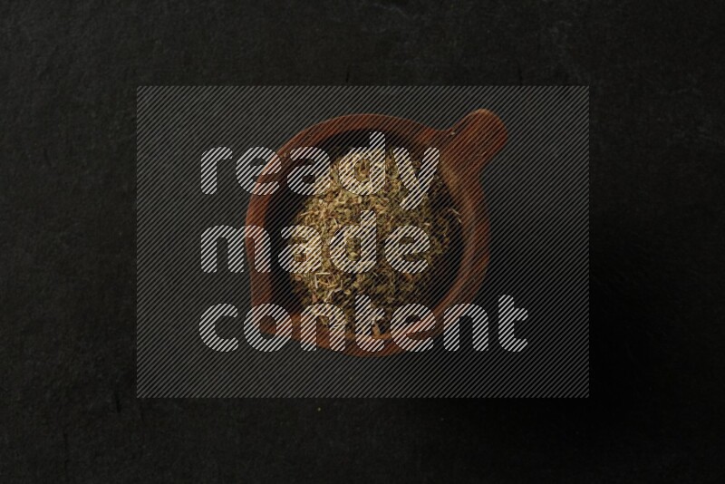 wooden round sauce bowl filled with herbs on grey textured countertop
