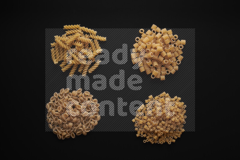 Different pasta types in bunches on black background