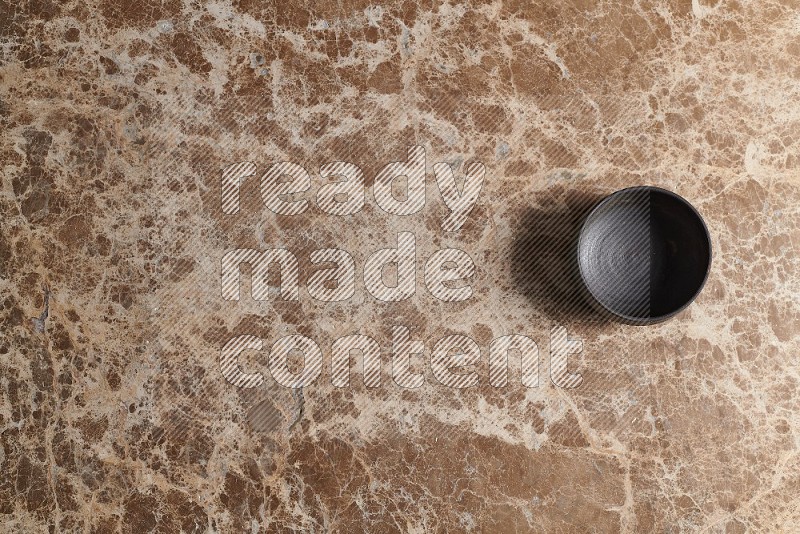 Top View Shot Of A Black Pottery Bowl On beige Marble Flooring