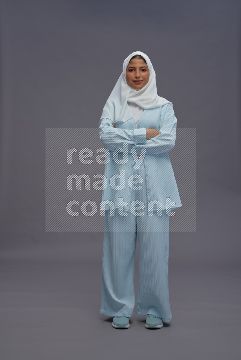 Saudi woman wearing hijab clothes standing with crossed arms on gray background
